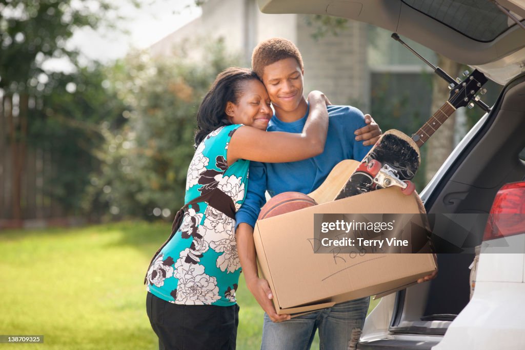 Mother hugging teenage son as he packs for college