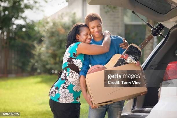 Mother hugging teenage son as he packs for college