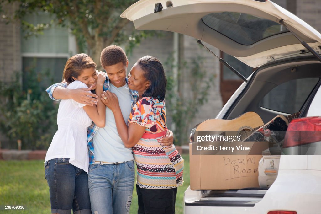 Family hugging teenage boy as he prepares for college