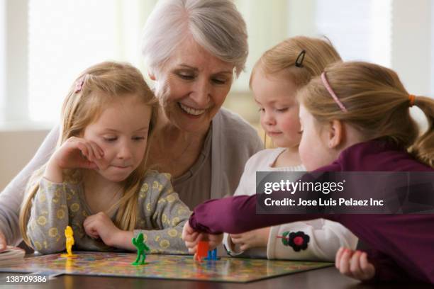 caucasian grandmother and granddaughters playing game together - 4 people playing games stock pictures, royalty-free photos & images