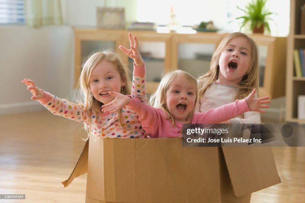 Caucasian sisters playing in cardboard box