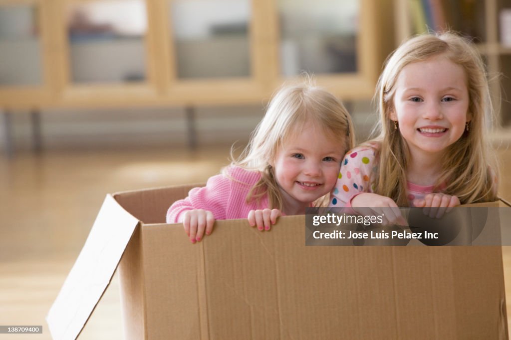 Caucasian sisters playing in cardboard box