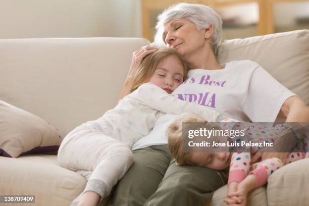 caucasian grandmother and granddaughters napping on sofa together - grandma sleeping stock pictures, royalty-free photos & images