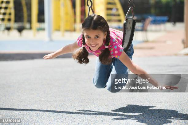 hispanic girl swinging on playground swing - girl long hair stock pictures, royalty-free photos & images