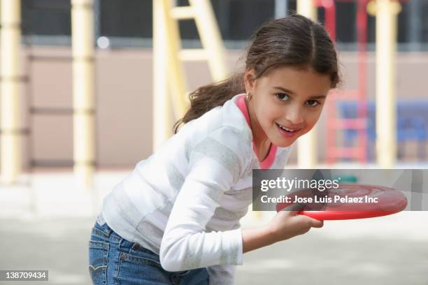 hispanic girl throwing plastic disc on playground - frisbee fotografías e imágenes de stock