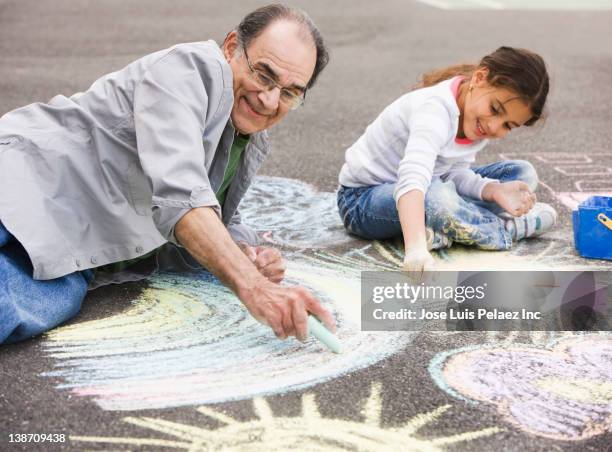 hispanic grandfather and granddaughter drawing on ground with chalk - west new york new jersey stock-fotos und bilder