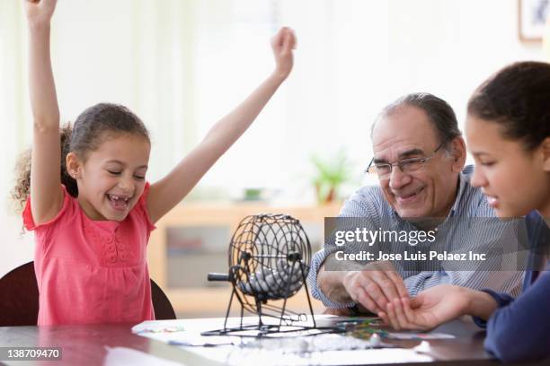 hispanic girls and grandfather playing game - bingo stock-fotos und bilder