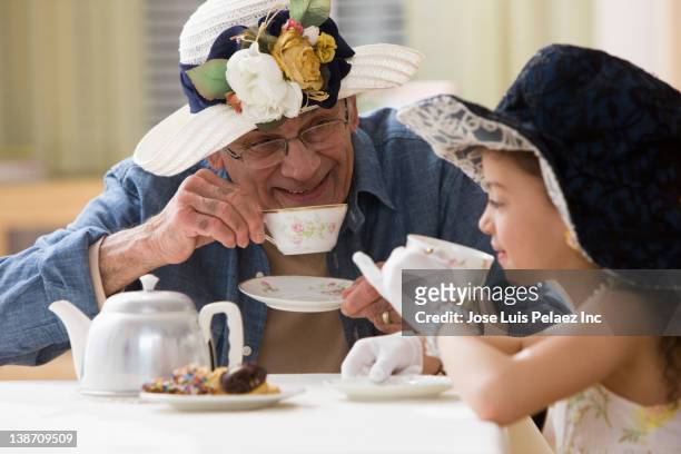 hispanic girl and grandfather having tea party - tea party stock pictures, royalty-free photos & images