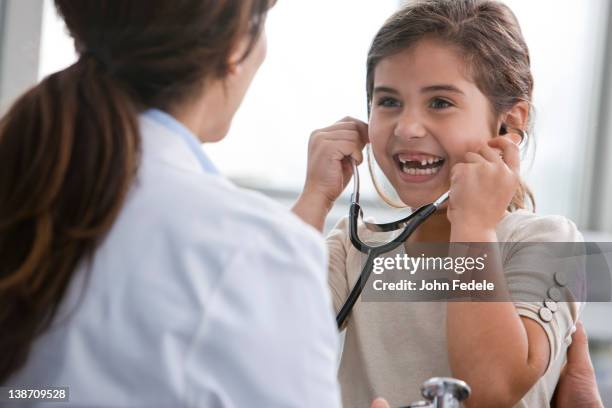doctor letting girl use stethoscope - latino child care stock pictures, royalty-free photos & images