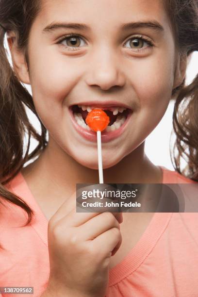 mixed race girl eating lollipop - lutscher stock-fotos und bilder