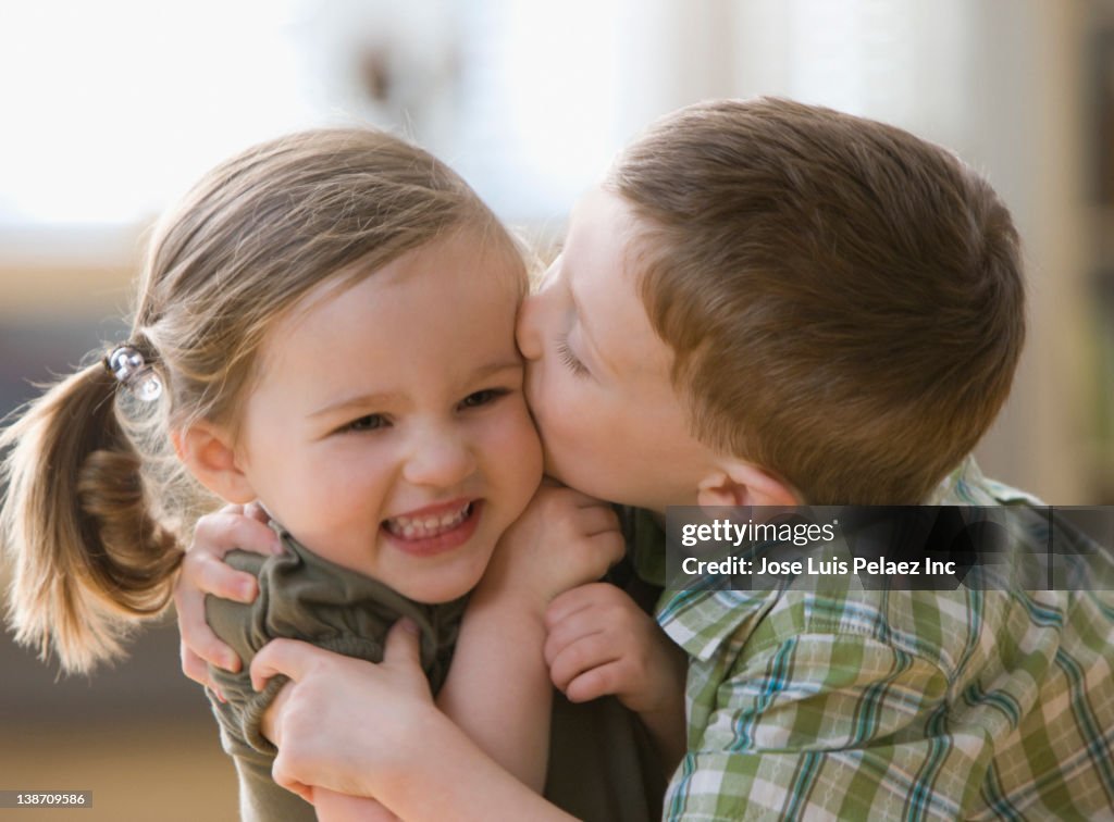Caucasian brother kissing sister