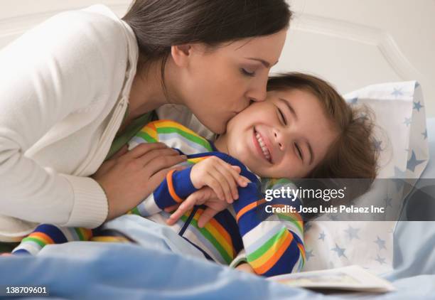 mother kissing son in bed - good night kiss stock-fotos und bilder