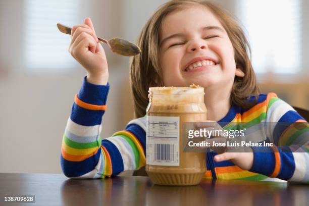 mixed race boy eating peanut butter - erdnussbutter stock-fotos und bilder