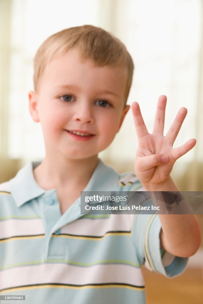 Caucasian boy holding up four fingers