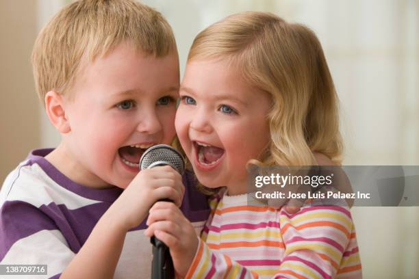 caucasian brother and sister singing into microphone - singing imagens e fotografias de stock