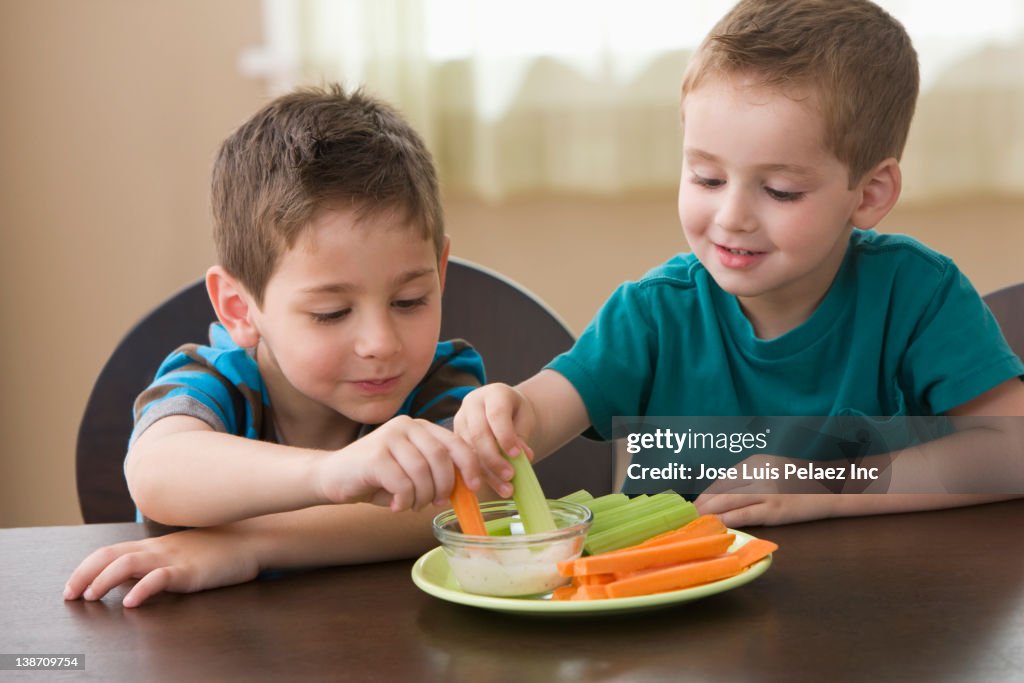 Caucasian brothers eating vegetables and dip