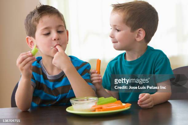 caucasian brothers eating vegetables and dip - kids dressing up stock-fotos und bilder