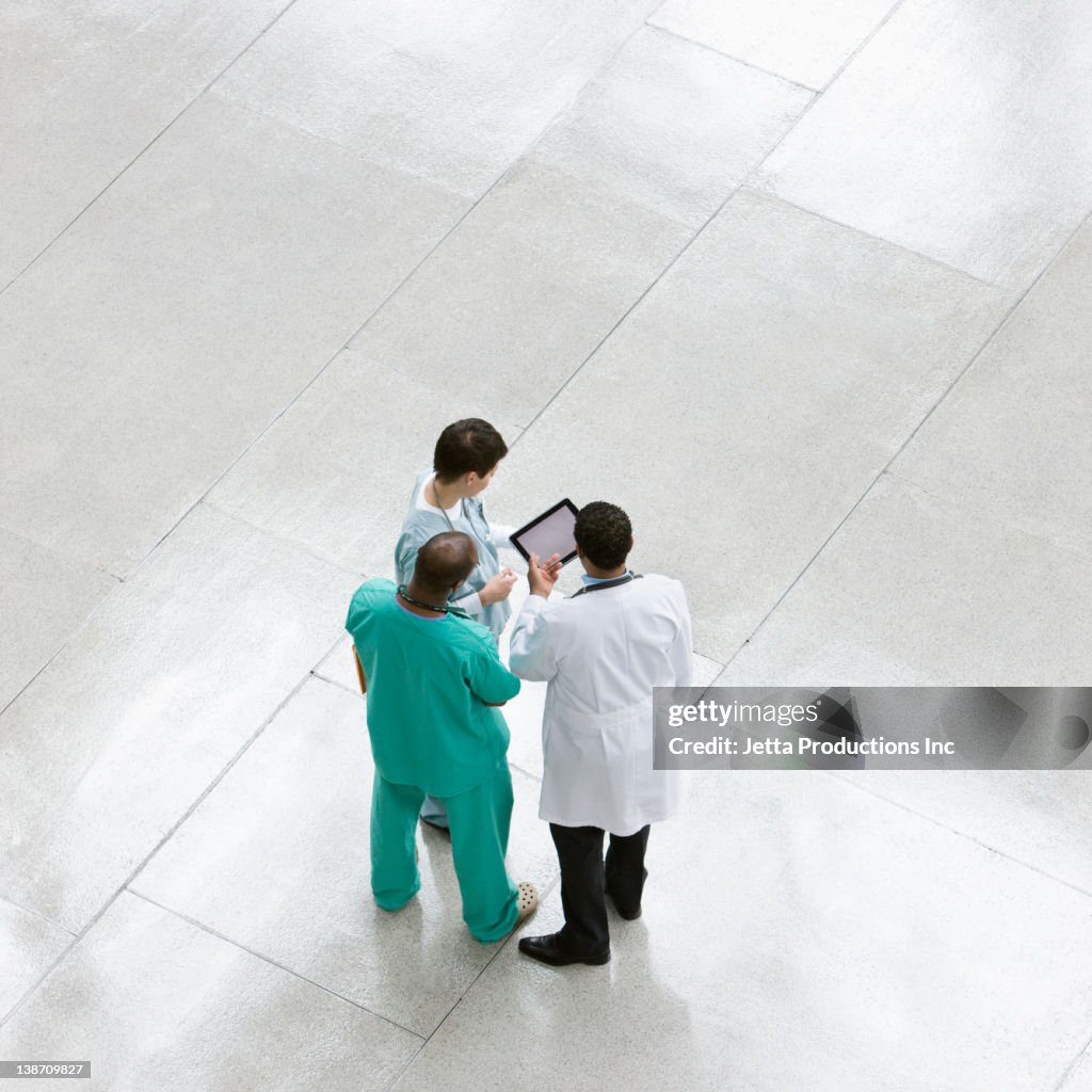 Doctors using digital tablet together in lobby