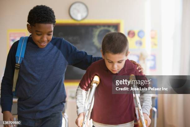 Boy walking with friend on crutches