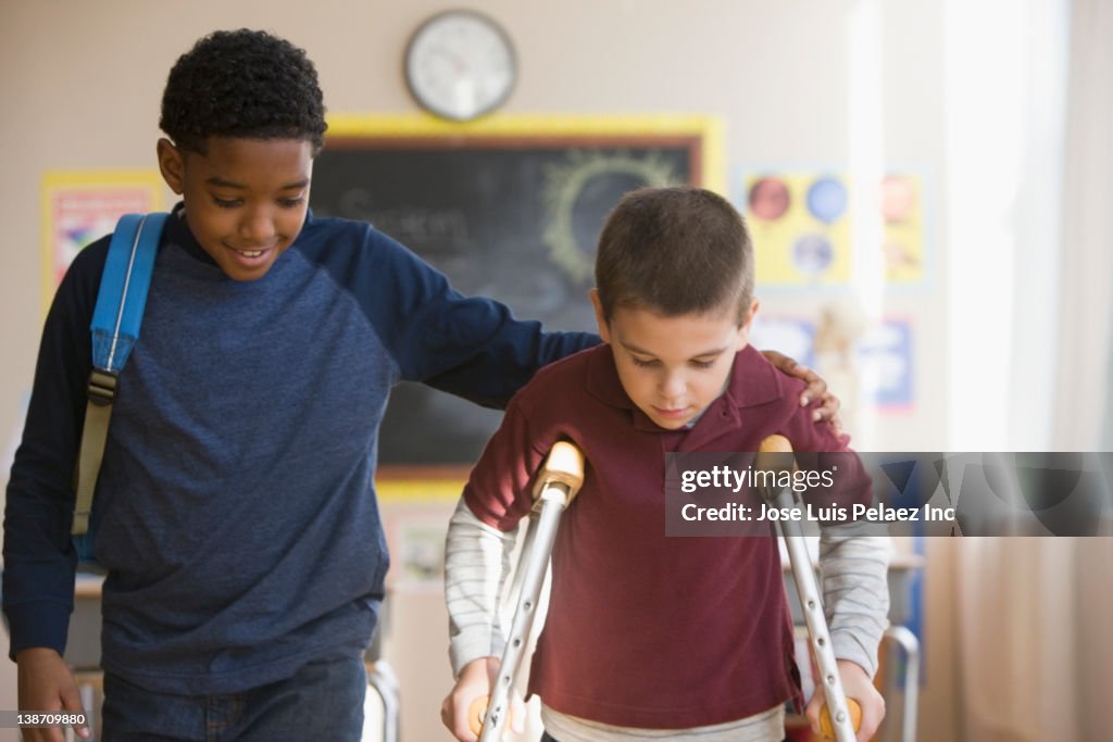 Boy walking with friend on crutches