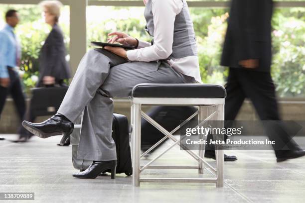 businesswoman using digital tablet in busy lobby - incidental people stock pictures, royalty-free photos & images