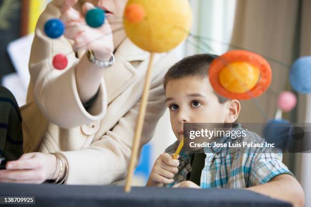 mixed race boy studying the planet model in classroom - school students science stock pictures, royalty-free photos & images