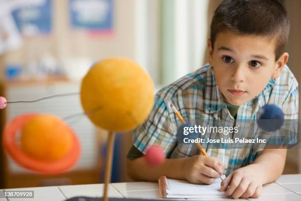 mixed race boy studying the planet model in classroom - criança de escola primária imagens e fotografias de stock