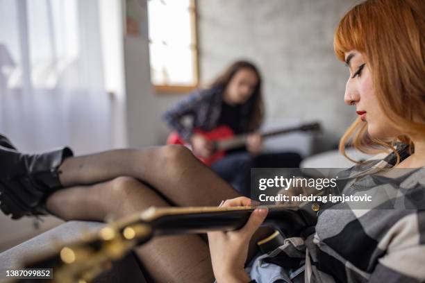 adolescente disfrutando tocando la guitarra eléctrica en casa - girl playing bass guitar fotografías e imágenes de stock