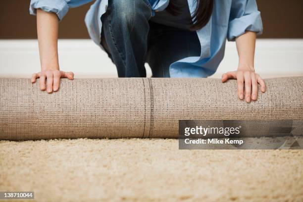 caucasian woman unrolling carpet - carpet stock pictures, royalty-free photos & images