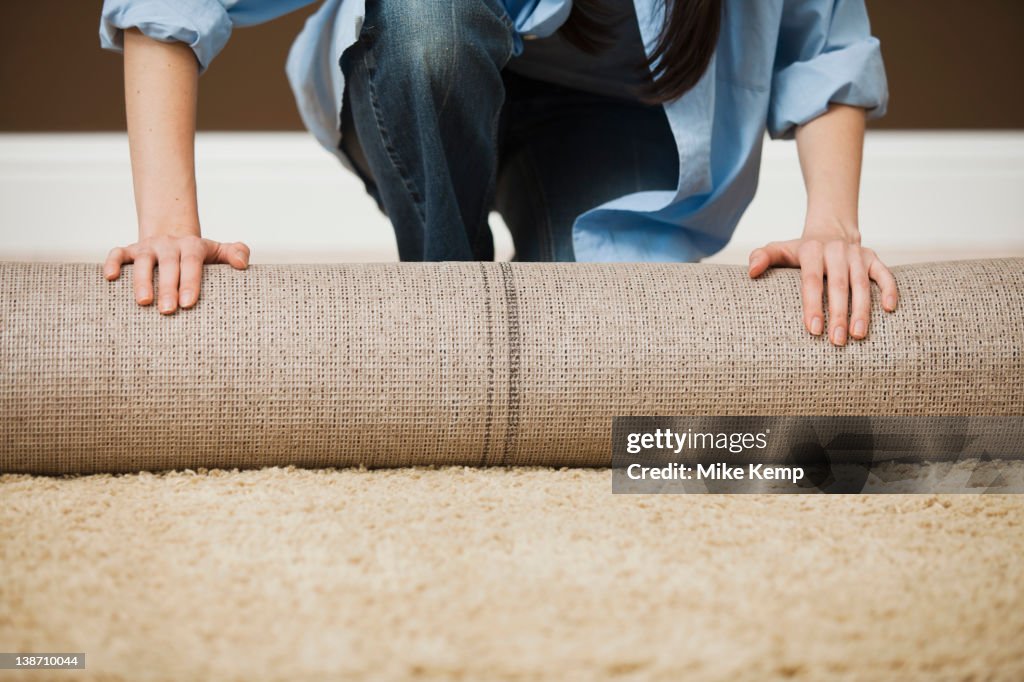 Caucasian woman unrolling carpet