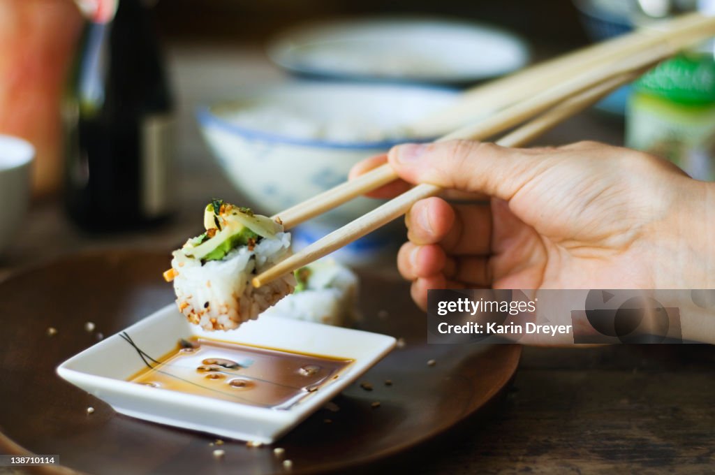 Person eating sushi with chopsticks