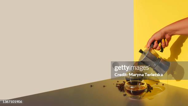 female hand with a coffee maker and a cup of coffee. background with food. coffee drink. - nah stock-fotos und bilder