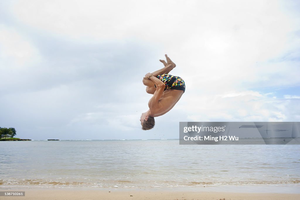 Caucasian man doing a flip on beach