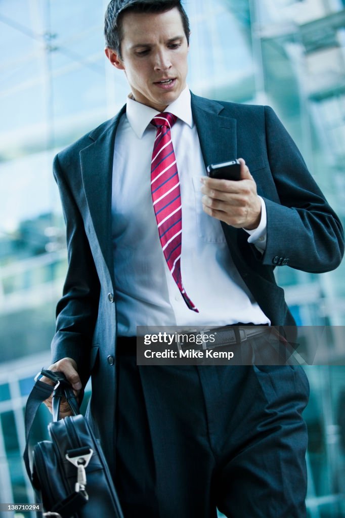 Caucasian businessman looking at cell phone outdoors