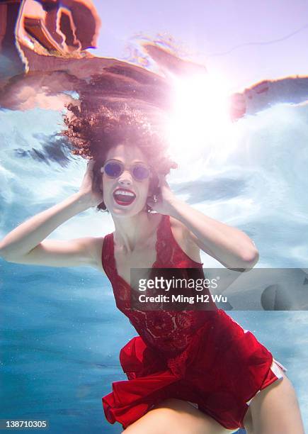 mixed race woman in clothes swimming underwater - women swimming pool retro stock pictures, royalty-free photos & images
