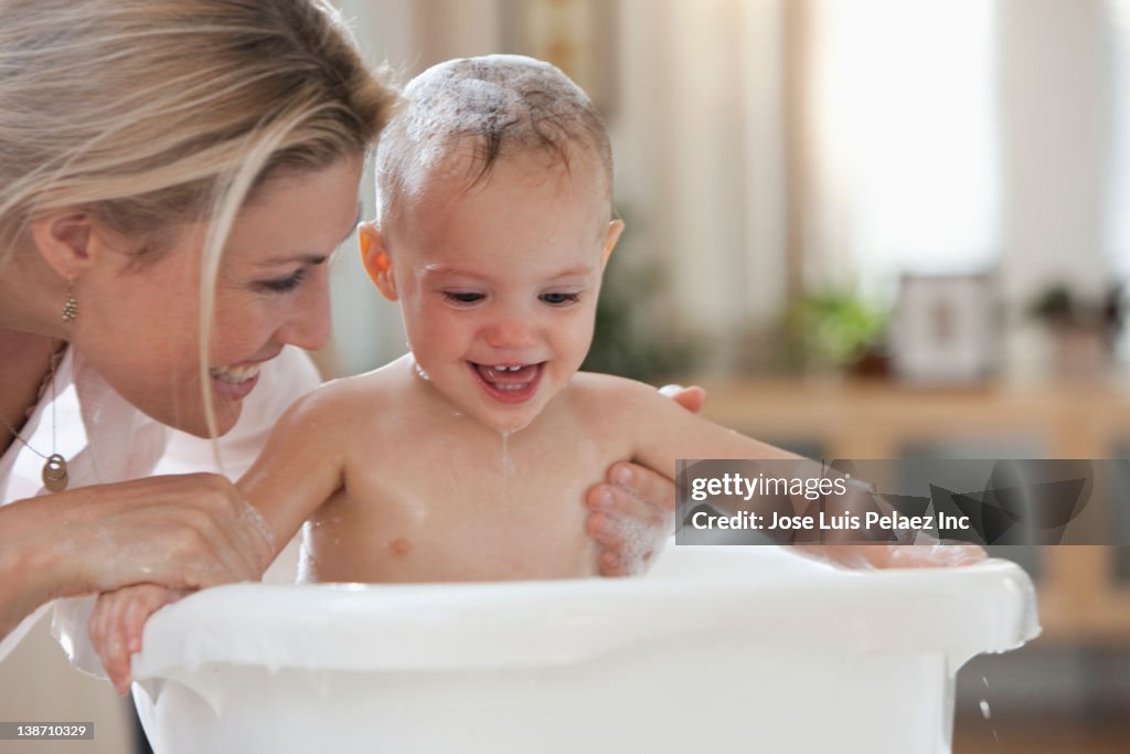 Caucasian mother giving baby daughter a bath