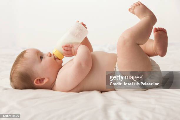 caucasian baby girl laying down drinking bottle - barefoot feet up lying down girl stock-fotos und bilder