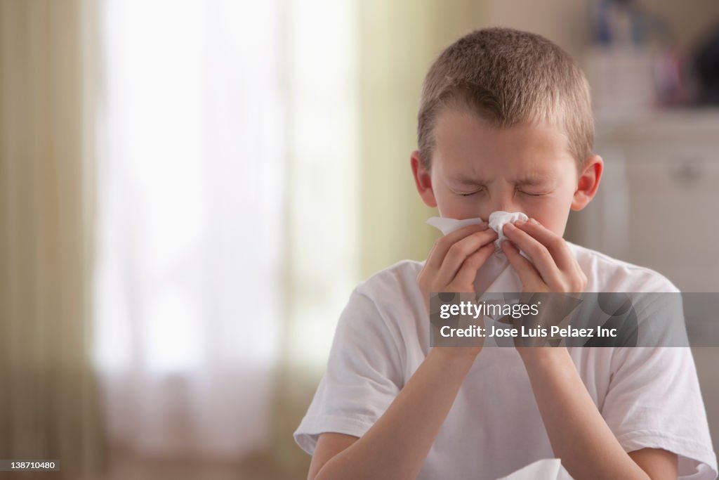 Caucasian boy blowing nose