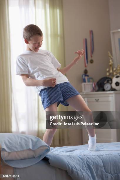 caucasian boy standing on bed playing air guitar - kids in undies stock pictures, royalty-free photos & images