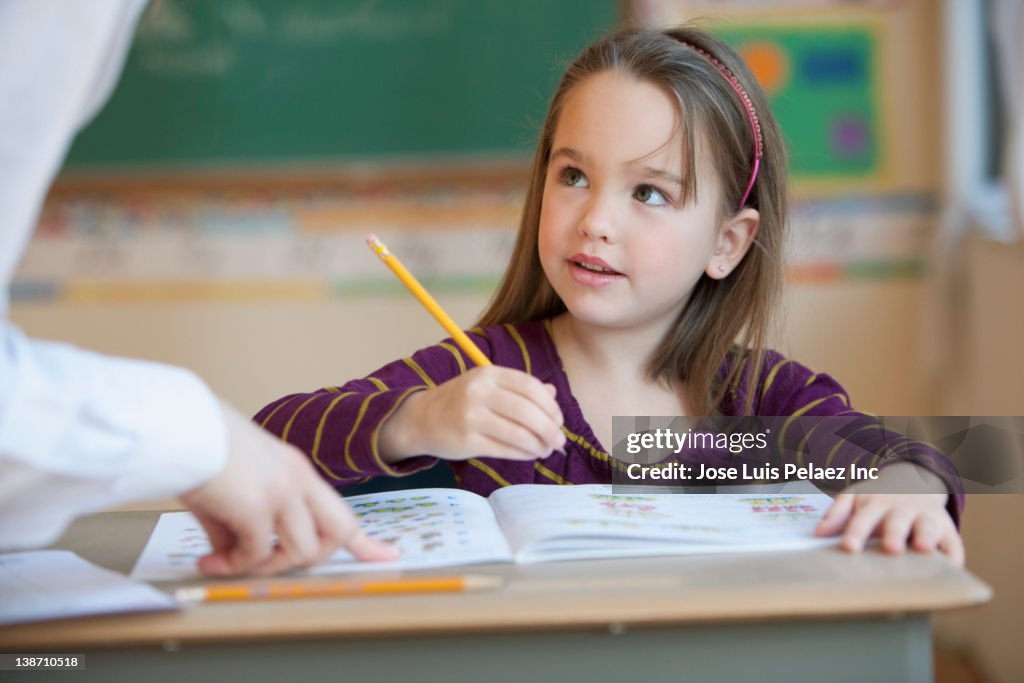 Teacher helping Caucasian girl studying in classroom