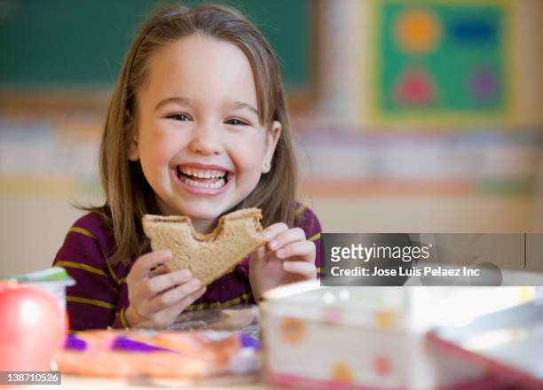 caucasian girl eating lunch in classroom - lunchbox stockfoto's en -beelden