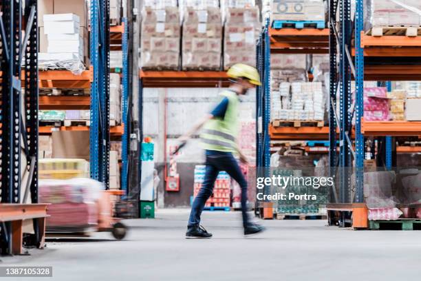 motion blur of a male employee moving boxes in warehouse - busy warehouse stock pictures, royalty-free photos & images