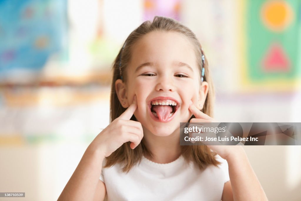 Caucasian girl making face in classroom