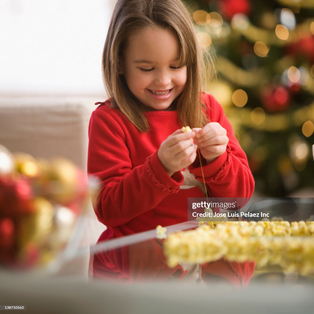 Caucasian girl stringing popcorn at Christmastime