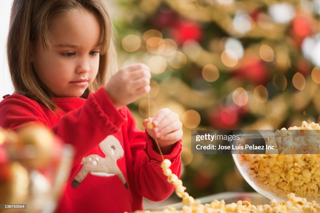 Caucasian girl stringing popcorn at Christmastime