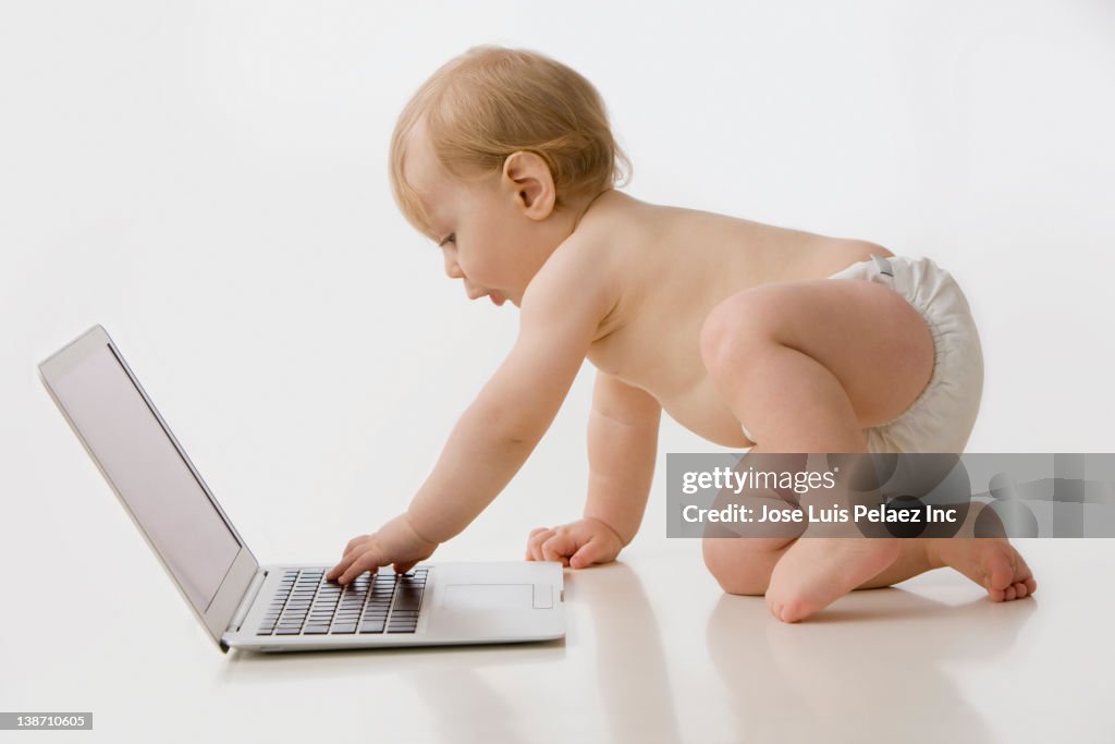 Caucasian baby boy typing on laptop