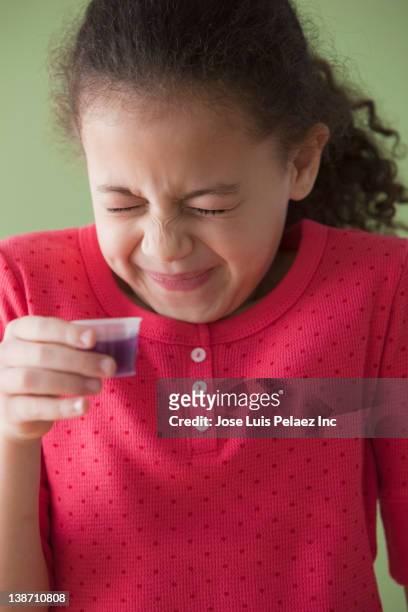 hispanic girl taking cough syrup - taste for a cure stock pictures, royalty-free photos & images