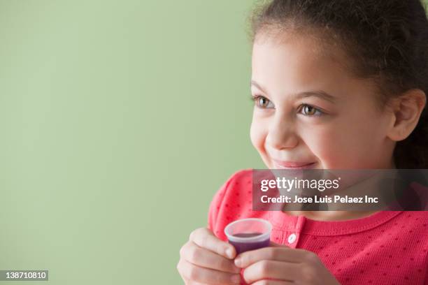 hispanic girl taking cough syrup - hustenmittel stock-fotos und bilder