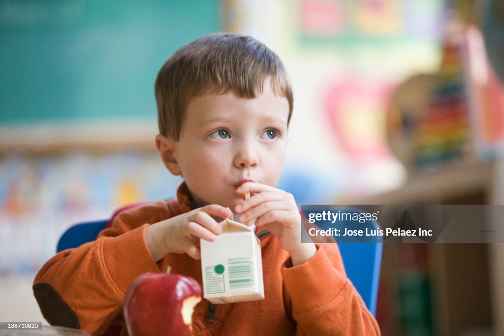 Caucasian boy eating lunch in classroom