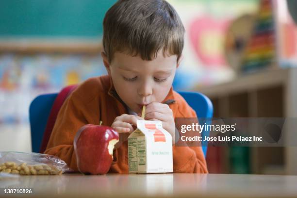 caucasian boy eating lunch in classroom - juice box stock pictures, royalty-free photos & images